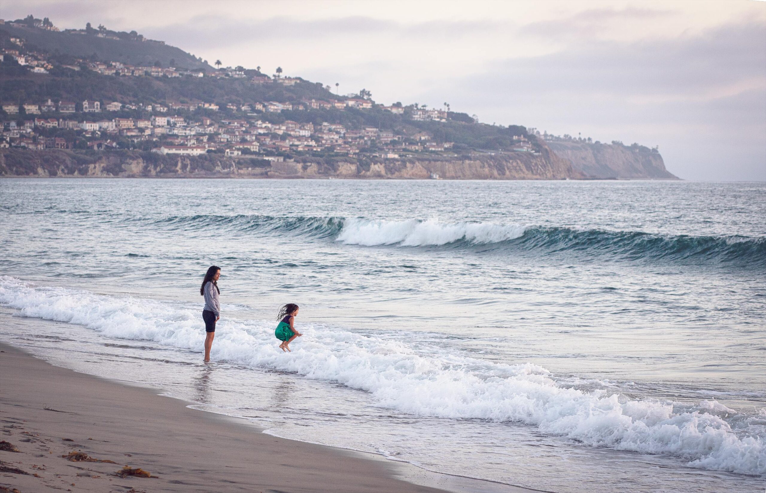 Mother and daughter enjoying the waves on the Redondo Beach coast, representing the stress-free lifestyle enabled by Next Wave Cleaning Services.